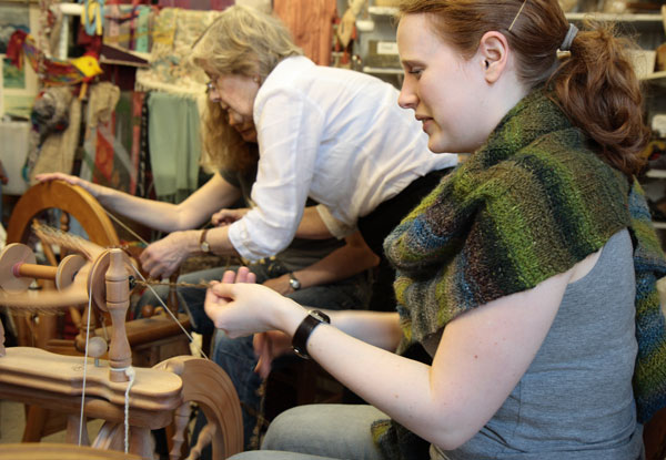 Laura plying strands together on the wheel Laura plying strands together on the wheel